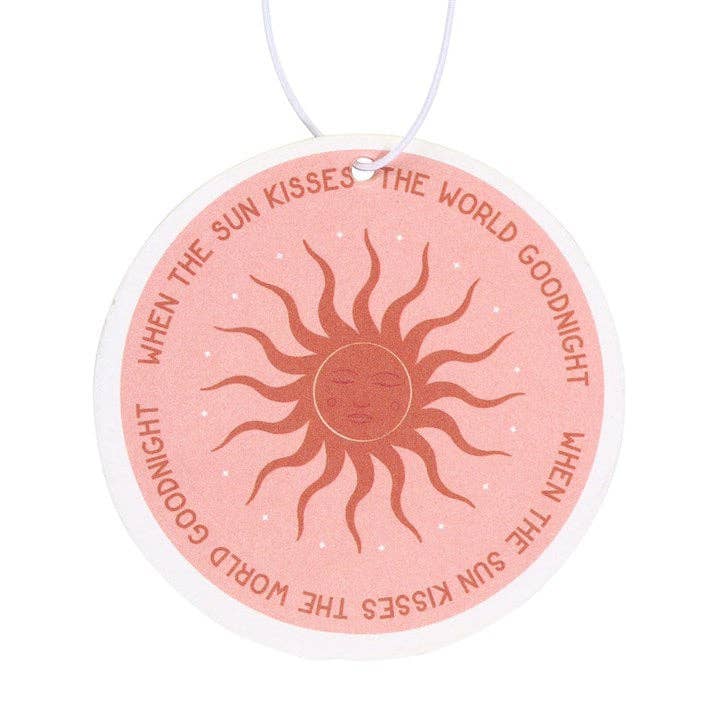 Round pink air freshener with sun design and text on a white background