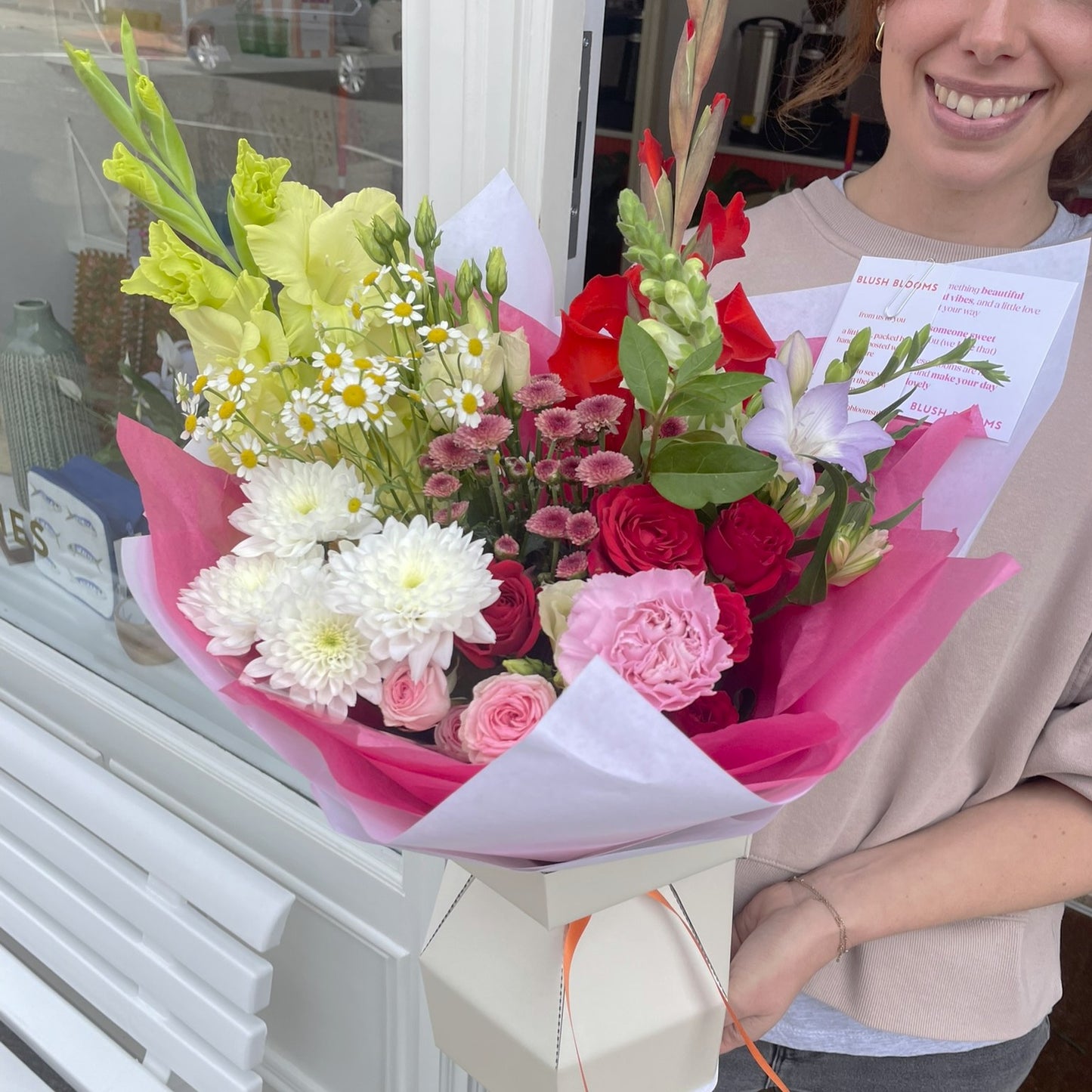 Person holding a colorful bouquet of flowers with a smiling face.