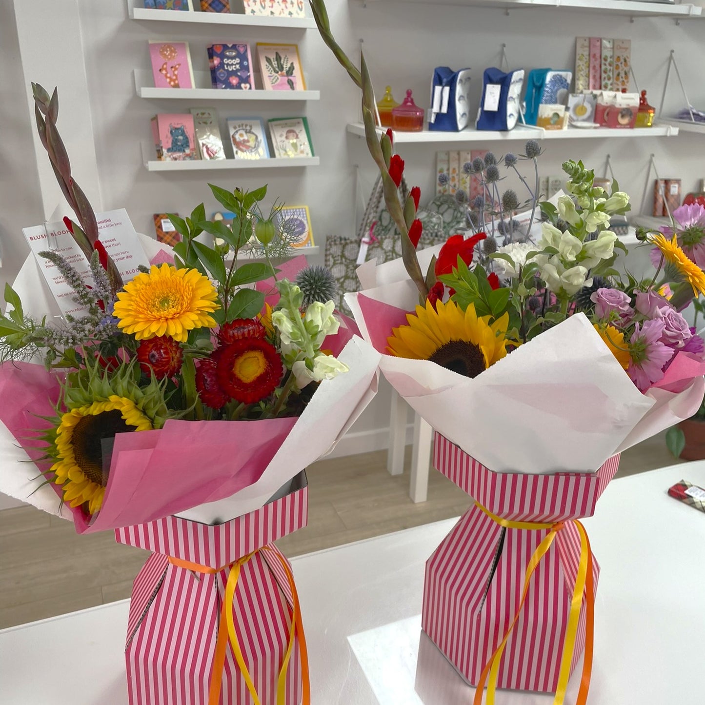Two flower bouquets in pink and white striped paper with yellow ribbons on a white surface.