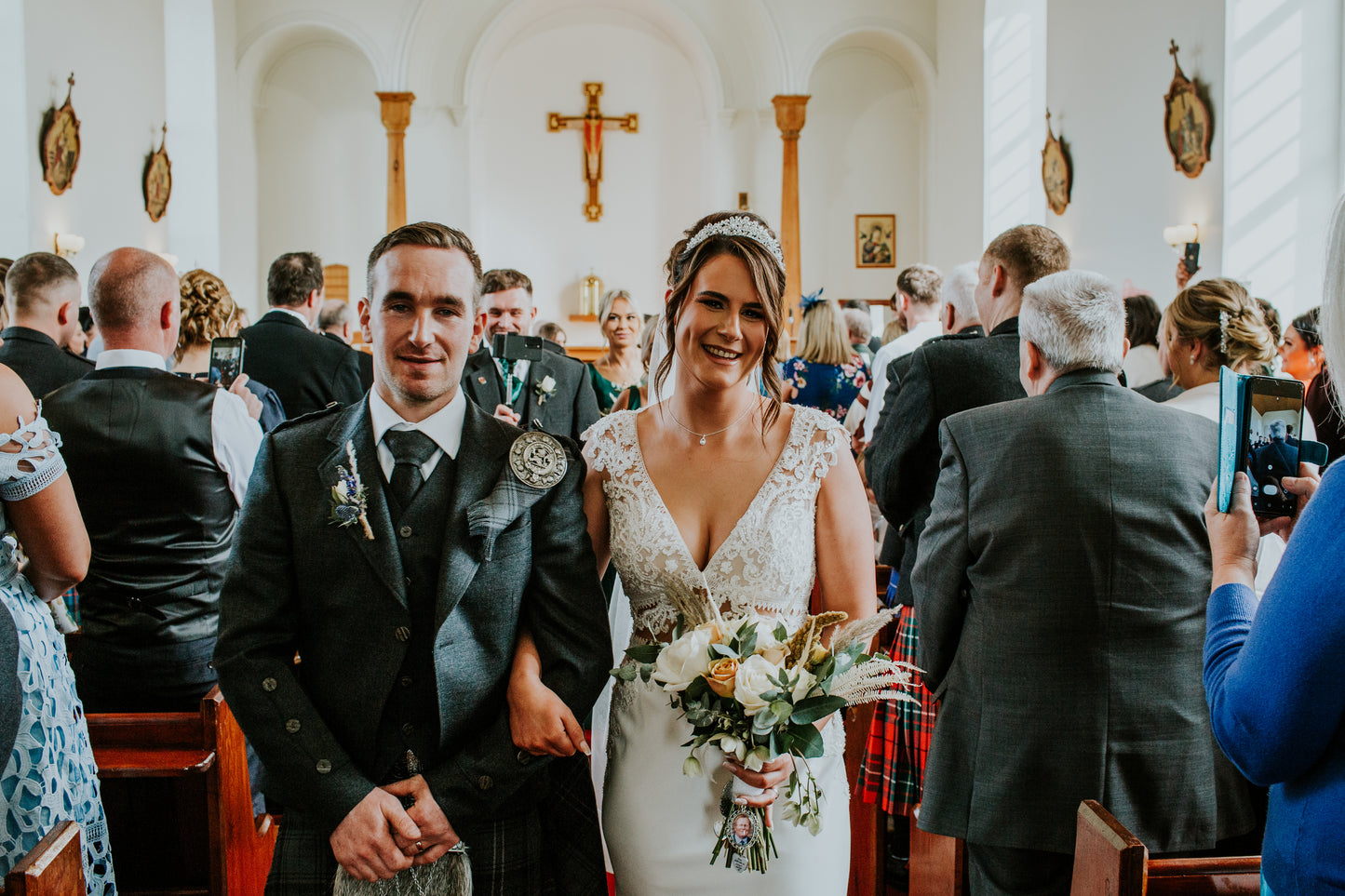 Couple in wedding attire standing in a church with guests around