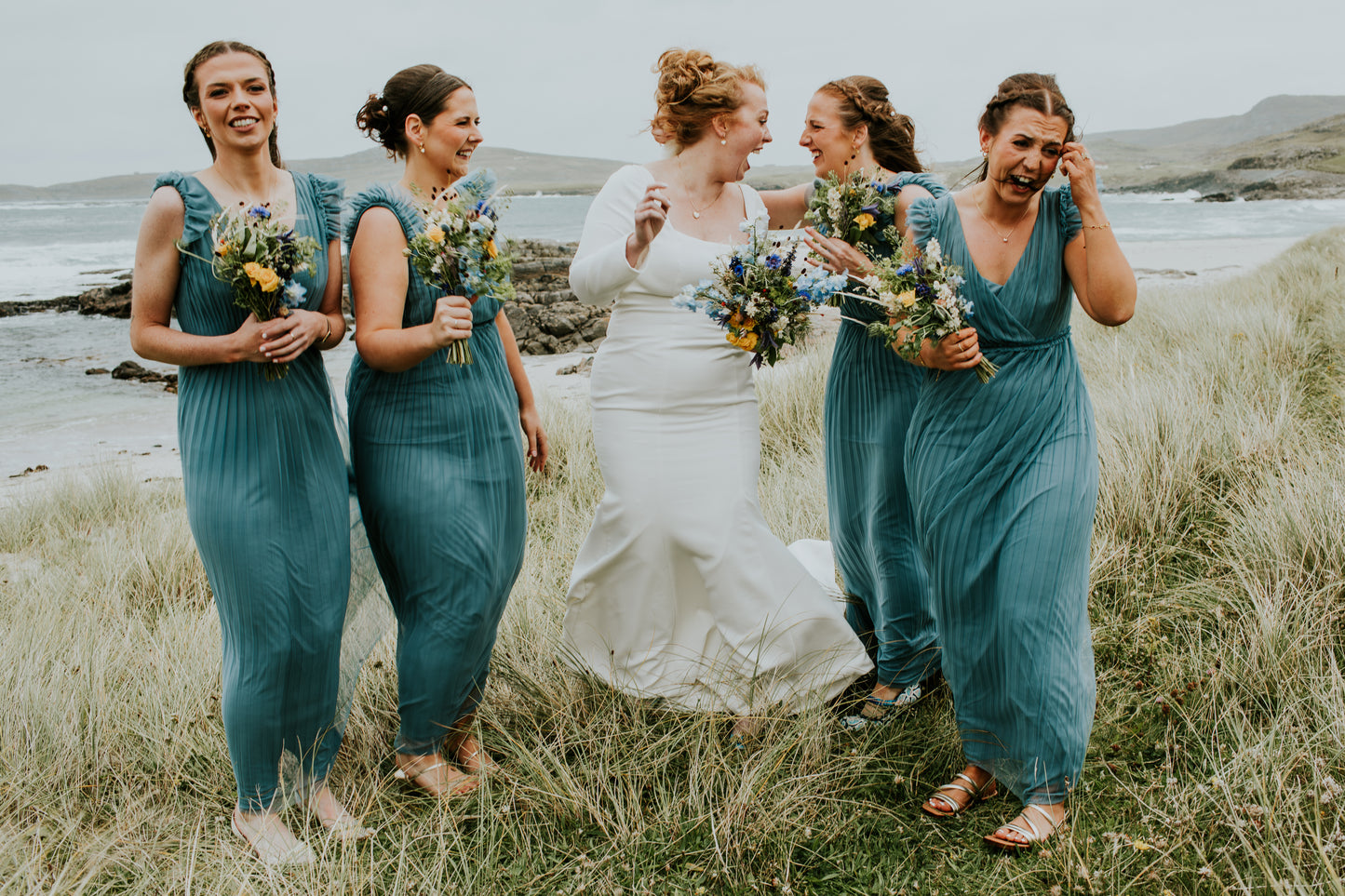 Bride with bridesmaids in teal dresses on a beach