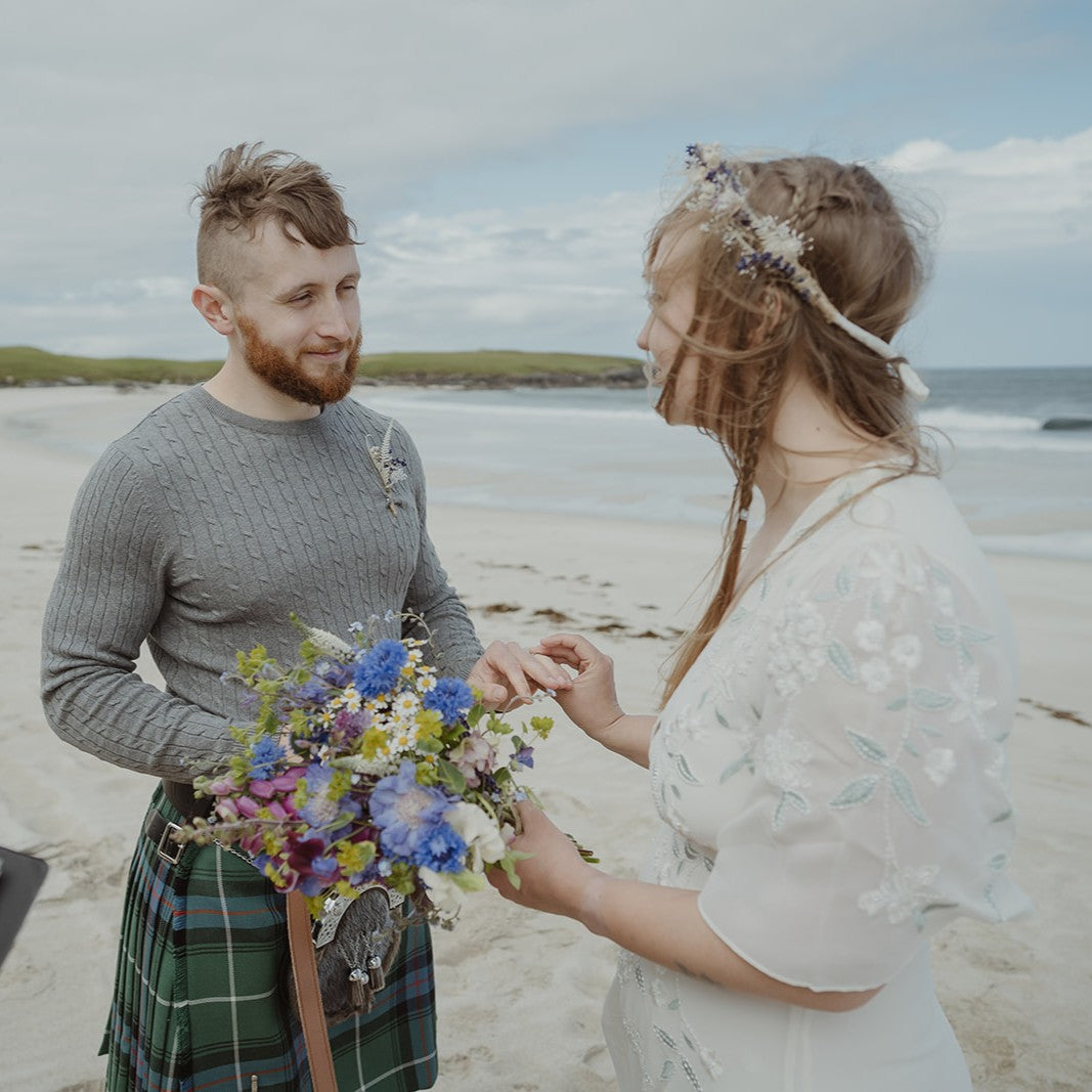 Bride holding wildflower elopement bouquet at beach wedding