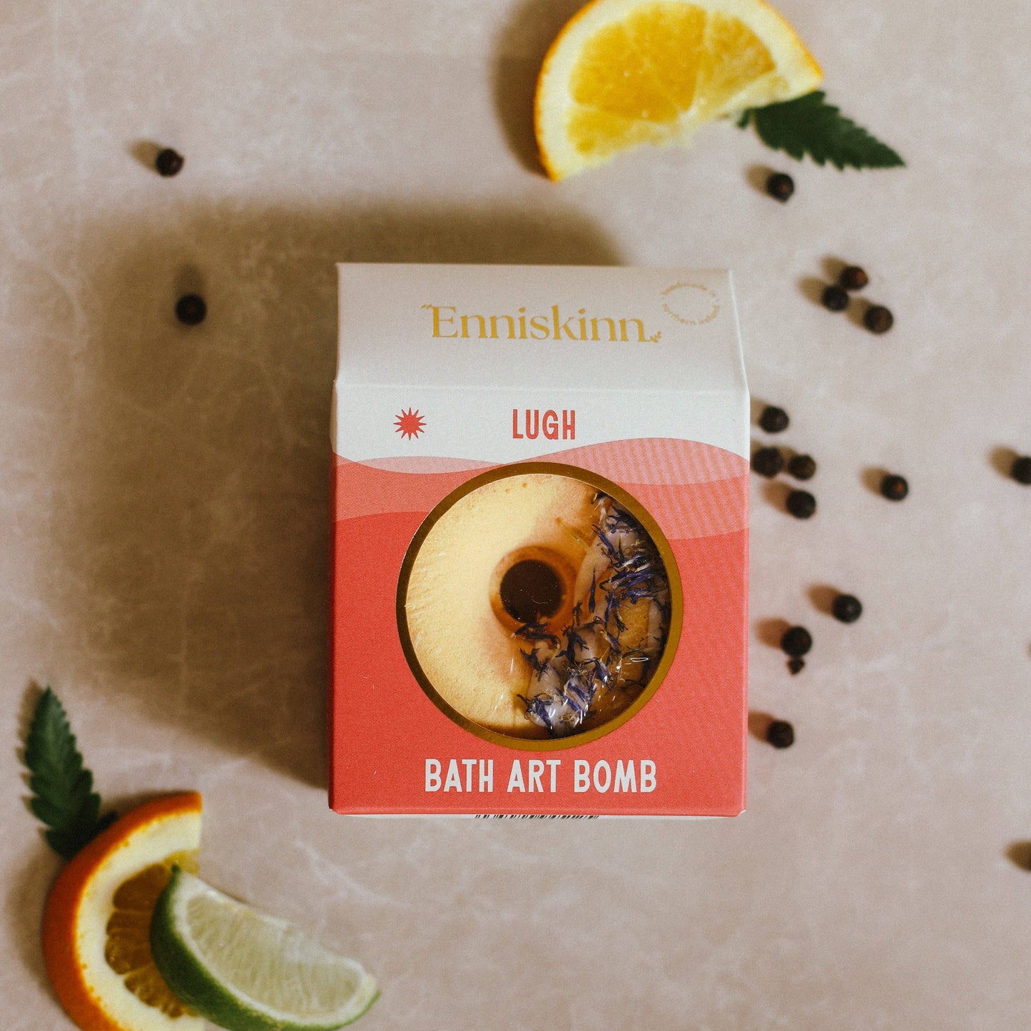 Enniskinn Lugh Bath Art Bomb packaging with oranges and leaves on a beige background
