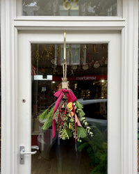 Decorative door swag with greenery and ribbons hanging on a door