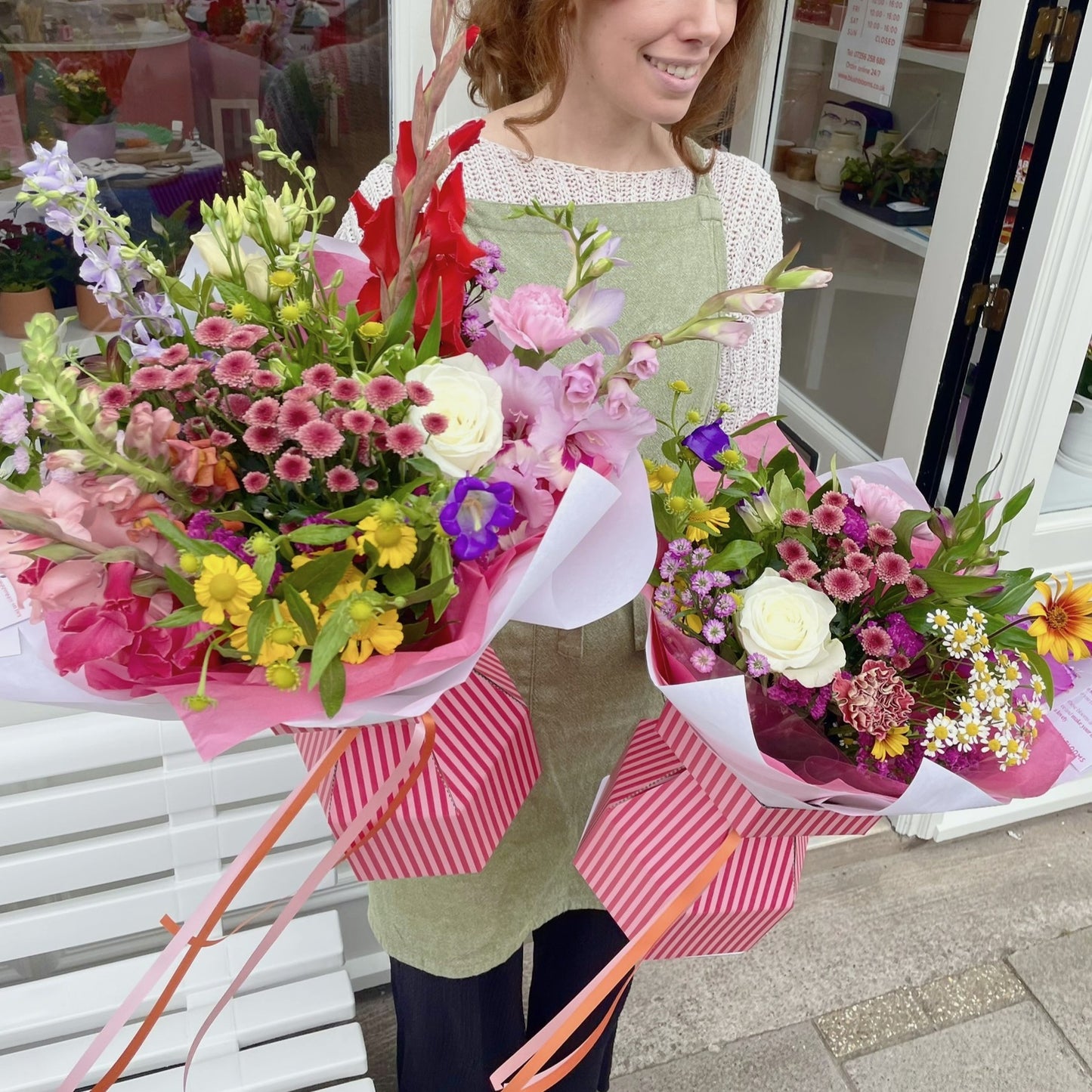 Woman holding two bouquets of flowers in a store setting