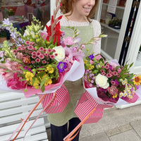 Woman holding two bouquets of flowers in a store setting