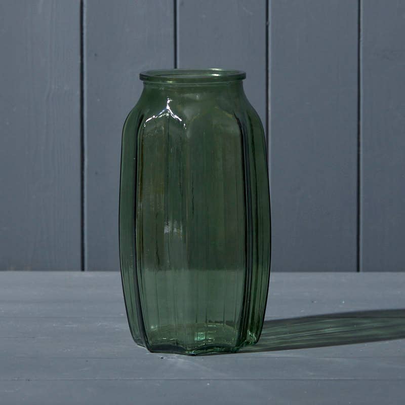 Green glass vase on a gray surface with a gray wooden background