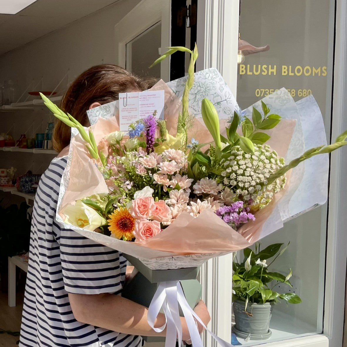 Person holding a luxury bouquet in front of Blush Blooms florist