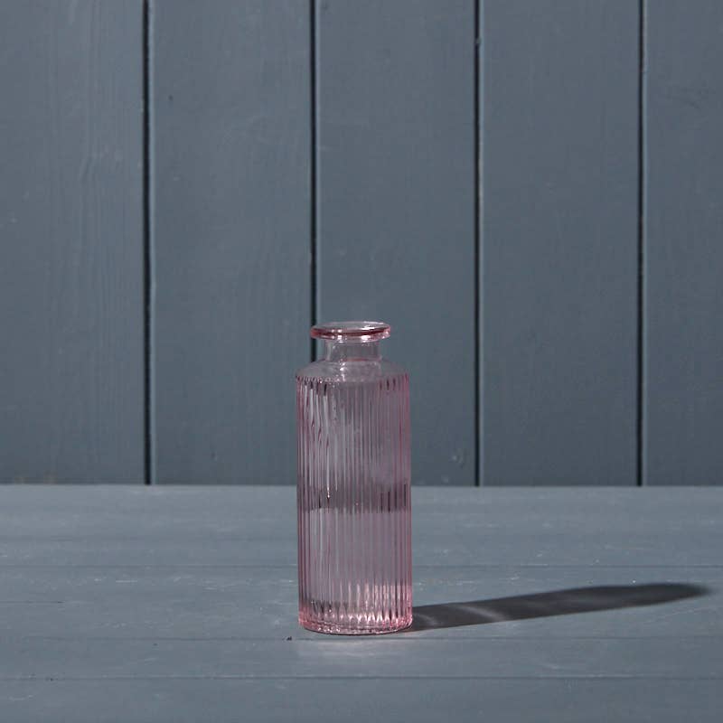 Pink glass bottle on a gray surface with a gray background