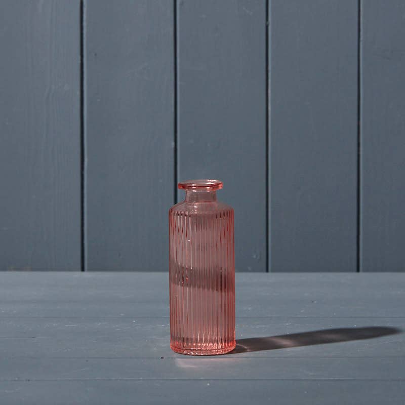 Pink glass bottle on a gray surface with a blue wooden background