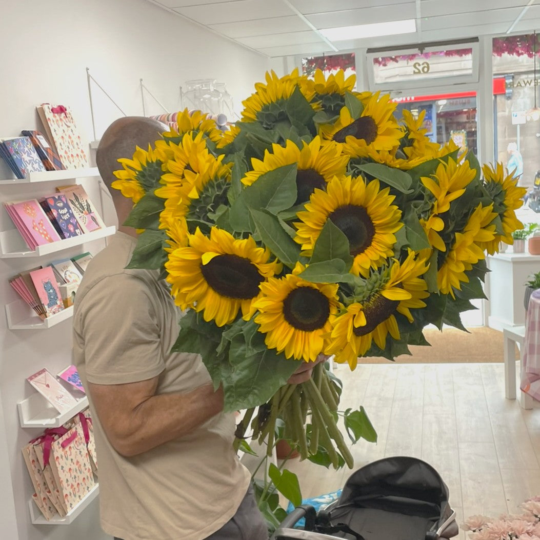 Person holding a large bouquet of sunflowers in Stonehaven florist shop