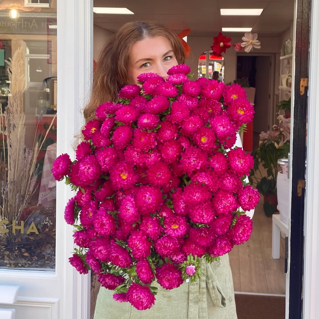 Florist holding a large bouquet of pink flowers in the door of the Stonehaven florist