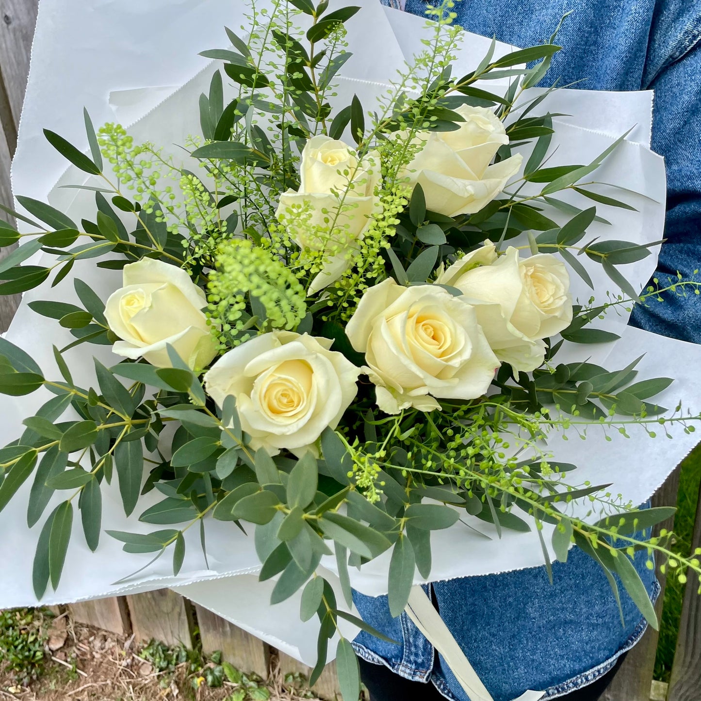 Bouquet of white roses with greenery on a white paper background
