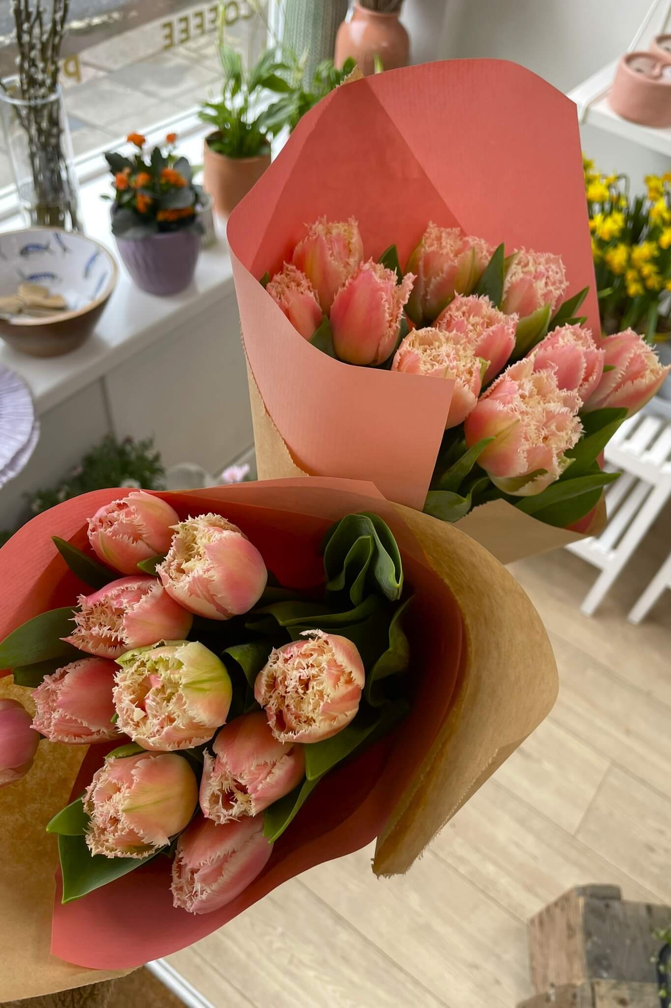 Bunches of frilly light pink tulips wrapped and ready to gift in a florist shop.