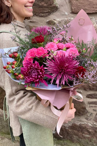Pink Berry bouquet featuring pink roses, berry stems and textured seasonal flowers, wrapped in blush paper.