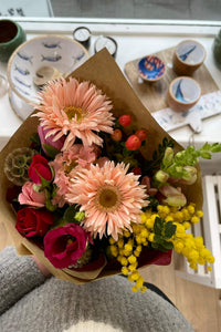 Colourful seasonal Thank You Posy with gerberas, roses, lisianthus and mimosa, wrapped in kraft paper.