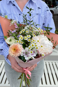 Person holding a soft peach, white and lilac seasonal teacher posy with peonies, dahlias, daisies and alstroemeria.
