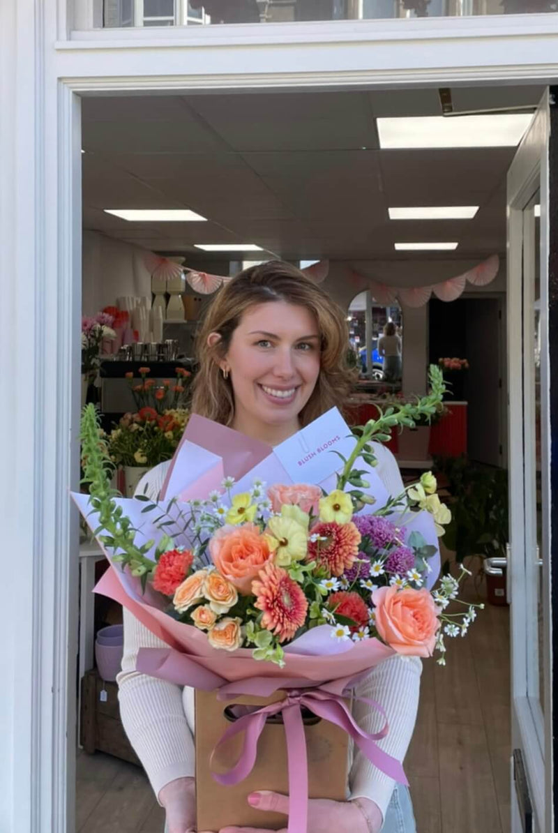 Seasonal Bouquet by Blush Blooms featuring peach roses, peach germini, spray roses, snapdragons and seasonal flowers.